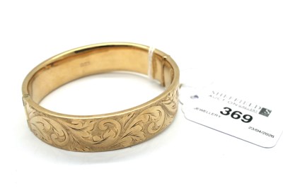 Lot 369 - A 9ct Gold Hinged Bangle, scroll engraved to...