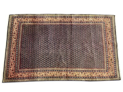 Lot 1579 - A Persian rug with repeat pattern in deep red...