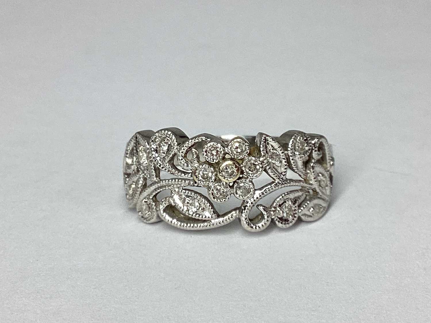Lot 65 - A Modern Millegrain Inset Floral Style Ring,...